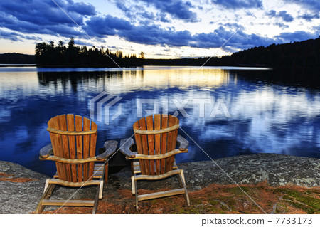 Wooden chairs at sunset on lake shore 7733173