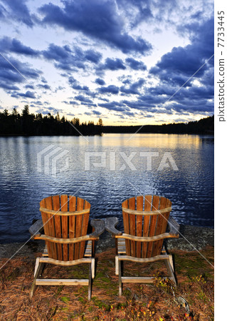 Wooden chairs at sunset on lake shore 7733445