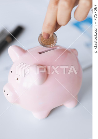 woman hand putting coin into small piggy ban woman hand putting coin into small piggy ban 7757067