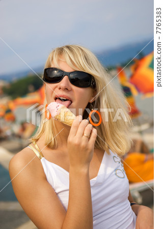 Beautiful young woman eating ice-cream on the beach Beautiful young woman eating ice-cream on the beach 7765383