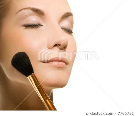 Beautiful young woman with a make-up brush. Isolated on white ba 7765781