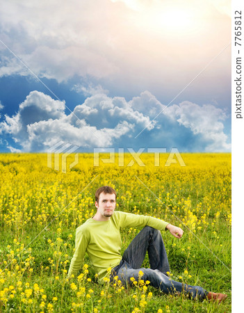 Relaxed young man sitting in a flower field Relaxed young man sitting in a flower field 7765812