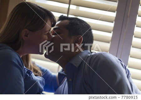 Mixed Race Couple Kissing Near the Light of the Window 7780915