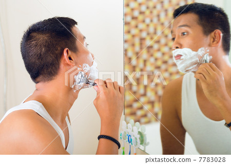 Asian man shaving in front of mirror Asian man shaving in front of mirror 7783028