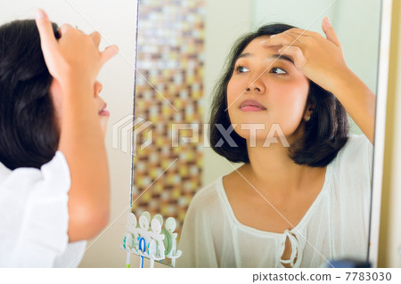 Asian woman discovering a pimple in face Asian woman discovering a pimple in face 7783030