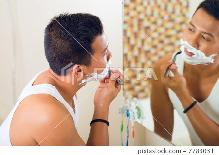 Asian man shaving in front of mirror Asian man shaving in front of mirror 7783031
