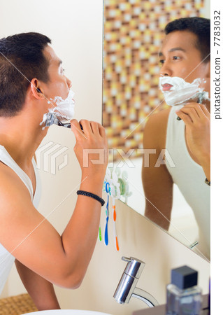 Asian man shaving in front of mirror Asian man shaving in front of mirror 7783032