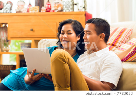 Asian people sitting in front of a notebook laughing Asian people sitting in front of a notebook laughing 7783033
