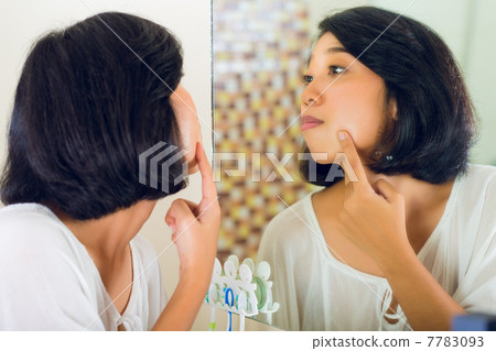 Asian woman discovering a pimple in face Asian woman discovering a pimple in face 7783093