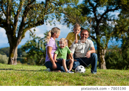 Family with children and football on a meadow 7803190