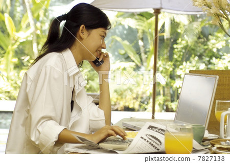 Young woman making phone calls while checking computer 7827138