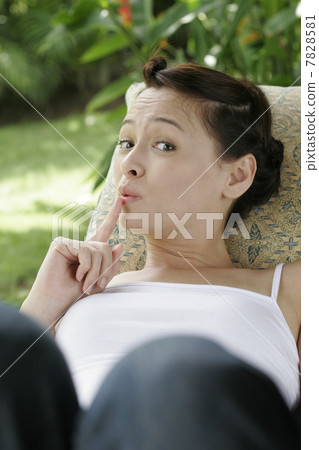 Young woman put finger on lips while lying 7828581