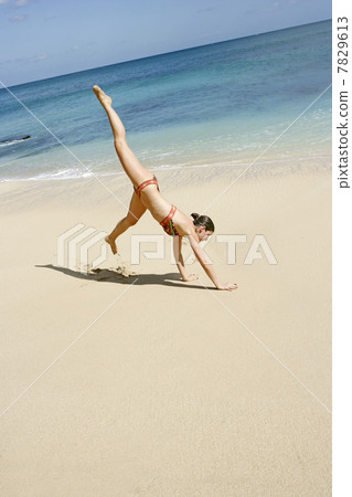 Young woman headstanding on the beach 7829613