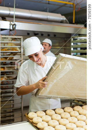 Female baker baking bread rolls Female baker baking bread rolls 7856599