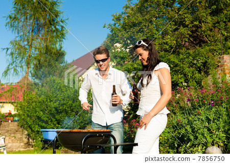 Couple doing BBQ in garden in summer Couple doing BBQ in garden in summer 7856750