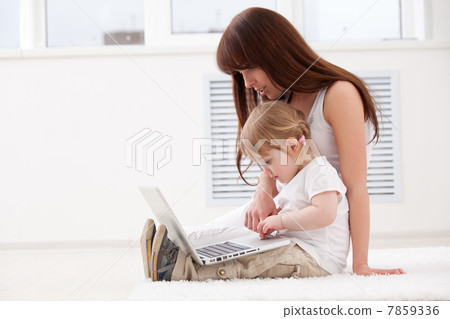 Happy young mother and her daughter using a laptop 7859336