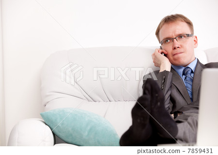 Good-looking young man seated on the sofa and talking at cellphone Good-looking young man seated on the sofa and talking at cellphone 7859431
