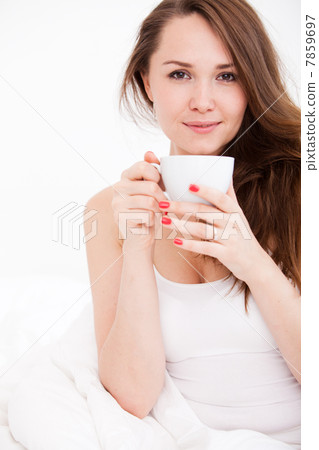portrait of woman in bed holding a cup 7859697