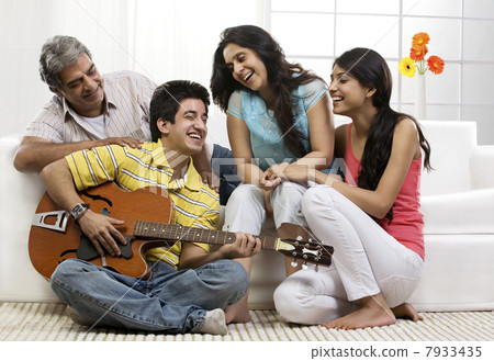 Boy playing the guitar for his family Boy playing the guitar for his family 7933435