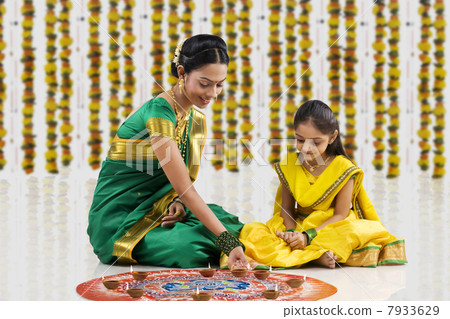 Woman arranging diyas on a rangoli Woman arranging diyas on a rangoli 7933629