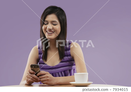 Woman reading an sms on a mobile phone Woman reading an sms on a mobile phone 7934015