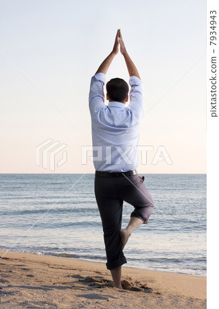 Businessman doing yoga on the beach 7934943