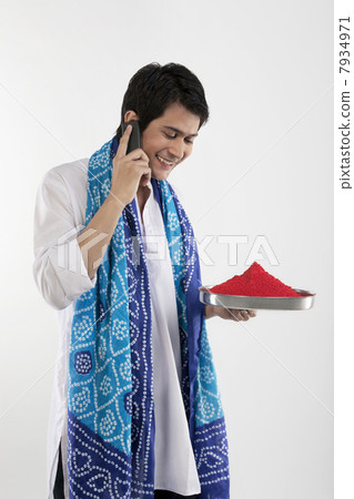 Man holding a tray of colours while talking on a mobile phone Man holding a tray of colours while talking on a mobile phone 7934971