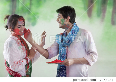 Man putting colour on a womans face 7934984