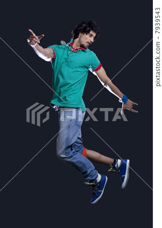 Young man in casual clothing dancing over black background 7939543
