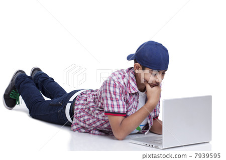 Teenage boy lying on front with laptop against white background 7939595