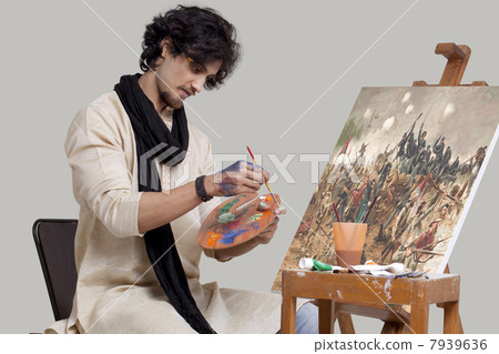 Young male artist mixing colors while painting 7939636