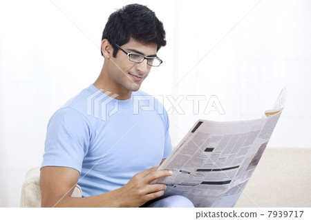 Young Indian man reading global news at home 7939717