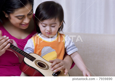 Mother playing a guitar for her son 7939890
