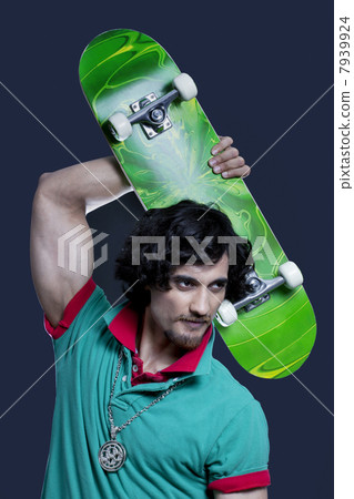 Young man posing with skateboard against black background 7939924