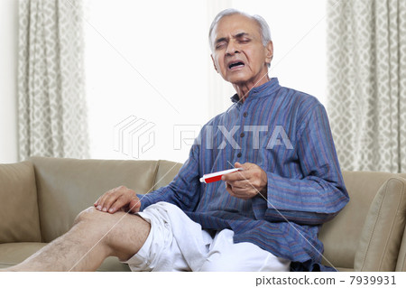 Elderly man applying ointment on knee 7939931