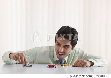Happy businessman playing with model car 7940066