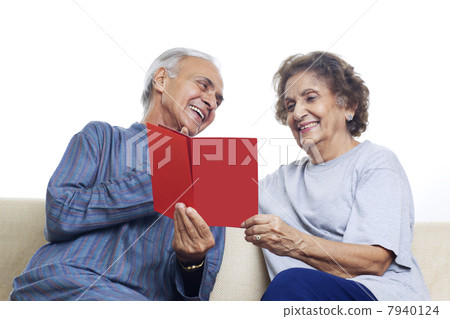 Senior couple smiling while looking at card 7940124