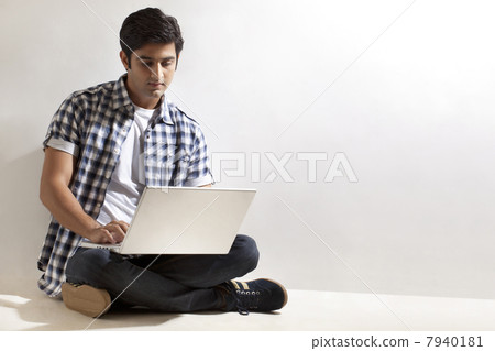Young man sitting on floor with laptop 7940181