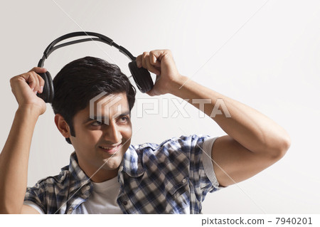 Handsome young man holding headphones and smiling Handsome young man holding headphones and smiling 7940201