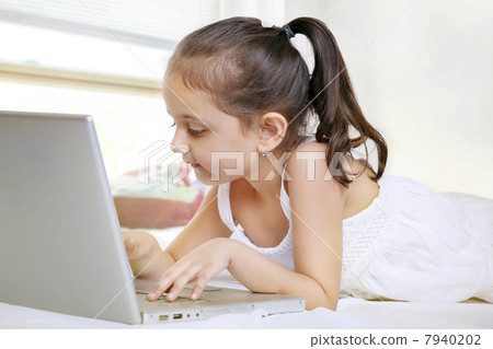 Girl using laptop while lying on bed Girl using laptop while lying on bed 7940202