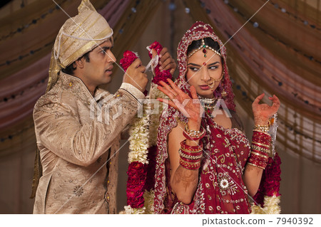 Indian groom trying to put a garland on his bride 7940392