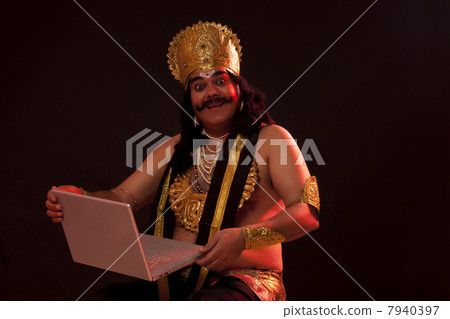 Portrait of a man dressed as Raavan with a laptop Portrait of a man dressed as Raavan with a laptop 7940397