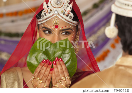 Bengali bride hiding her face from the groom 7940418