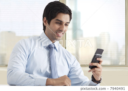 Happy young male executive reading text message 7940491