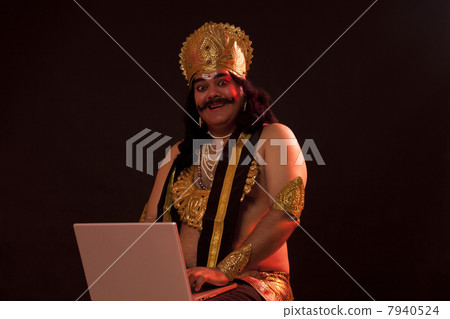 Portrait of a man dressed as Raavan with a laptop 7940524
