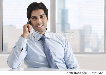 Portrait of smiling businessman speaking on phone call at office 7940564
