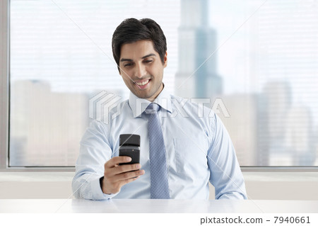 Happy young businessman texting message through cell phone Happy young businessman texting message through cell phone 7940661