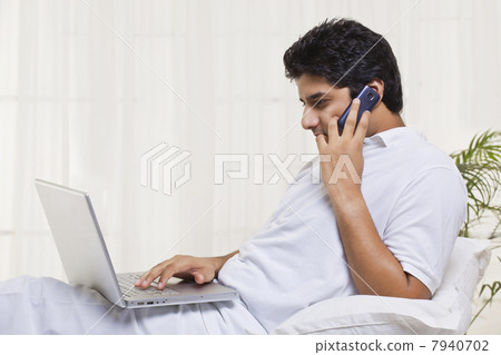 Young man having conversation while using laptop 7940702