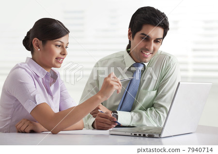 Two businesspeople preparing presentation while using laptop 7940714