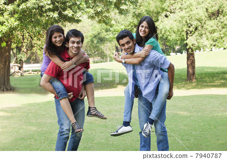 Couples piggybacking on campus and looking away Couples piggybacking on campus and looking away 7940787